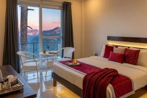 a bedroom with a bed and a table and a balcony at Shivansh Hotel in Kānda