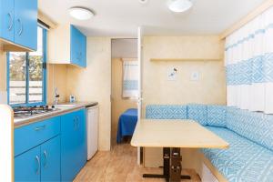 a small kitchen with a blue couch and a table at Camping Car Palmasera in Cala Gonone +39 photos