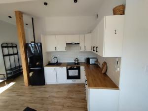 a kitchen with white cabinets and a black refrigerator at Apartament Karmelicka in Wadowice +1 photo