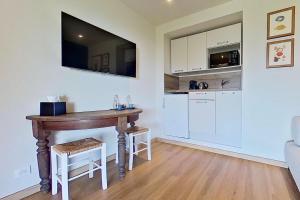 a kitchen with white cabinets and a wooden table at La Lézardière - Suites de Prestige & Spas Privatifs in Porto-Vecchio +6 photos