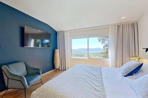 a bedroom with a bed and a chair and a window at La Lézardière - Suites de Prestige & Spas Privatifs in Porto-Vecchio
