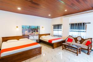 a bedroom with two beds and a couch and a chair at Lucas Hotel in Kosgoda