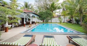 a swimming pool with two lounge chairs and a house at Lucas Hotel in Kosgoda +6 photos