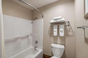 a white bathroom with a toilet and a bath tub at Ramada Bayside Inn & Suites Eureka in Eureka +28 photos