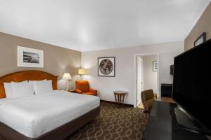 a hotel room with a bed and a flat screen tv at Ramada Bayside Inn & Suites Eureka in Eureka