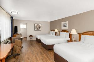 a hotel room with two beds and a desk at Ramada Bayside Inn & Suites Eureka in Eureka