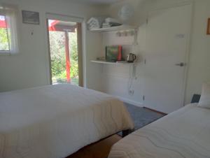 a white bedroom with two beds and a window at Rata Lodge Accommodation in Otira