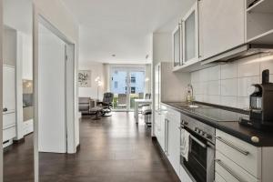 a kitchen with white cabinets and a living room at Ferienwohnung Landblick im Markgräflerland mit kostenlosem Parkplatz in Bad Bellingen