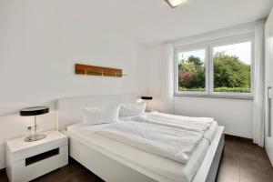 a white bedroom with a white bed and a window at Ferienwohnung Landblick im Markgräflerland mit kostenlosem Parkplatz in Bad Bellingen