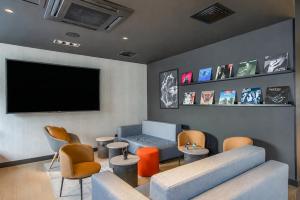a living room with a flat screen tv and chairs at Ibis Clermont-Ferrand Centre Stade in Clermont-Ferrand