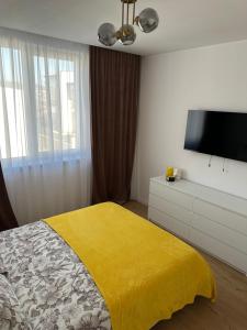 a bedroom with a yellow bed and a flat screen tv at Paradise Relax Apartament in Zalău