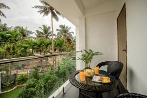 a balcony with a table and chairs and palm trees at Go Offline Homes - Designer 2BHK with Pool Near Candolim in Parra