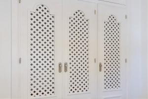 a white cabinet with three doors and three windows at Finca Isla Verde in Chipiona