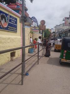 a group of people standing on a sidewalk next to a fence at Om Sai Manjunatha Residency in Puttaparthi
