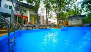 a large swimming pool with blue water in front of a house at Namusori pension in Koesan