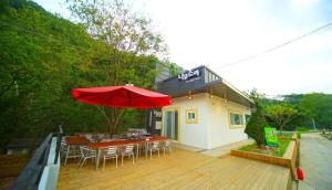 a patio with a red umbrella and a table and chairs at Namusori pension in Koesan