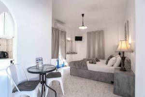 a bedroom with a bed and a table and chairs at Hotel Pleasure Blackbeach Santorini in Perissa