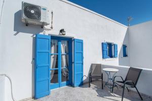 a house with a blue door and a tv on a balcony at Hotel Pleasure Blackbeach Santorini in Perissa