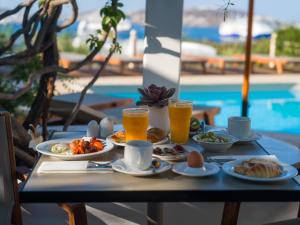 a table with breakfast foods and drinks on it at Rhenia Mykonos Hotel & Bungalows in Tourlos