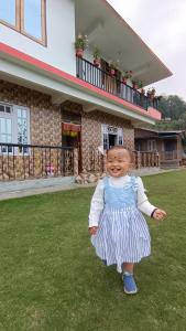 a little girl in a dress standing in the grass at Dhim in Mangpu