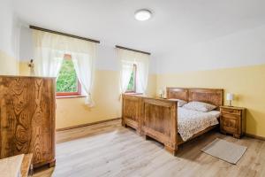 a bedroom with a wooden bed and two windows at Holiday house Pod Ledinco in Most na Soči
