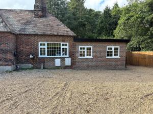 a brick house with white windows on a gravel driveway at Gatwick 'Bit on the Side' in Copthorne