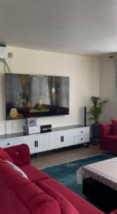 a living room with a red couch and a flat screen tv at Aranya Villa in Bākhri Kharka