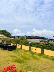 a fence with tables and chairs on the grass at Aranya Villa in Bākhri Kharka +3 photos