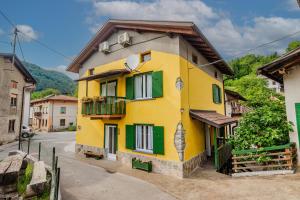 a yellow and green building with green shutters at Farmhouse Cvetje in Tolmin