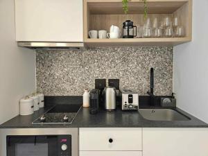 a kitchen counter with a sink and a microwave at High-Floor Modern Apartment - Rooftop Pool & Table Mountain Views in Cape Town