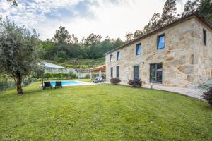 a stone house with a yard and a pool at Casa De Pedra D'alborinhas in Arões
