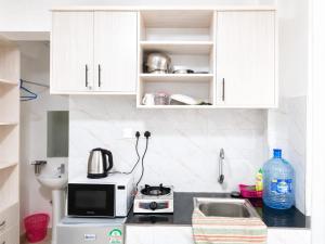 a kitchen with white cabinets and a microwave and a sink at Annie's studio near Westside mall in Nakuru