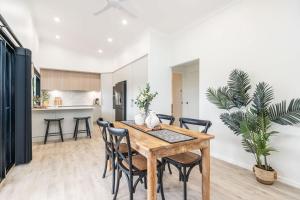 a kitchen and dining room with a wooden table and chairs at The Luxe Breeze Bungalow in Hervey Bay