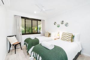 a white bedroom with two beds and a window at The Luxe Breeze Bungalow in Hervey Bay