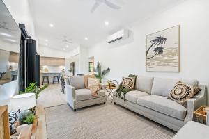 a living room with two couches and a kitchen at The Luxe Breeze Bungalow in Hervey Bay