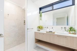 a bathroom with a sink and a mirror at The Luxe Breeze Bungalow in Hervey Bay +20 photos