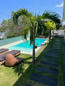 a pool with two palm trees and a swimming pool at Sari Hills Bali in Nusa Dua