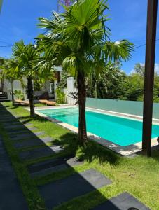 a swimming pool with palm trees next to a house at Sari Hills Bali in Nusa Dua