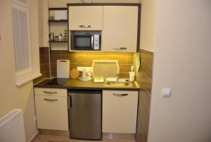 a small kitchen with a sink and a microwave at Bodza Apartmanok in Eger