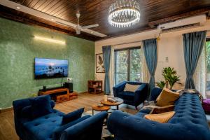 a living room with blue couches and a tv at Go Offline Homes - Designer 2BHK with Pool Near Candolim in Parra
