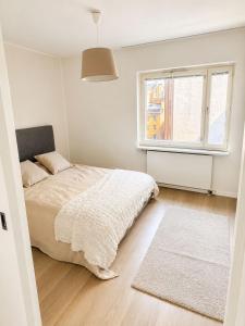 a white bedroom with a bed and a window at City Home Kalliossa in Helsinki