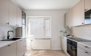 a white kitchen with a sink and a window at City Home Kalliossa in Helsinki