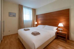 a bedroom with a large white bed with a wooden headboard at Seeappartement Altaussee - Your Austrian Home in Altaussee