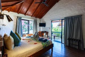 a bedroom with a bed and a large window at Colibri Hotel in Baie Sainte Anne