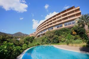 a hotel with a swimming pool in front of a building at Pleasure Resort Izu Akazawa Onsen in Ito
