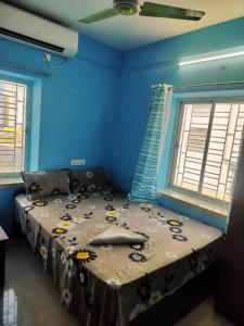 a blue bedroom with a bed with flowers on it at Priya guest house in Howrah