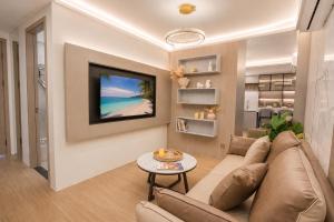 a living room with a couch and a tv on a wall at 1BR Solice Apartment Capri in Ban Thalat Choeng Thale
