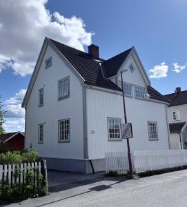 a white house with a white fence in front of it at Nyoppusset leilighet i klassisk hus! in Lillehammer