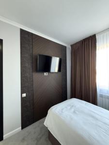 a bedroom with a bed and a flat screen tv on a wall at Karibi in Kyzylorda