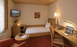 a hotel room with a bed and a desk with a laptop at DORMERO MaHo Steyr in Steyr